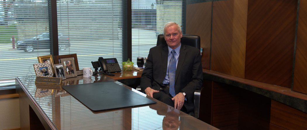 Tom Beck sitting and smiling at his desk